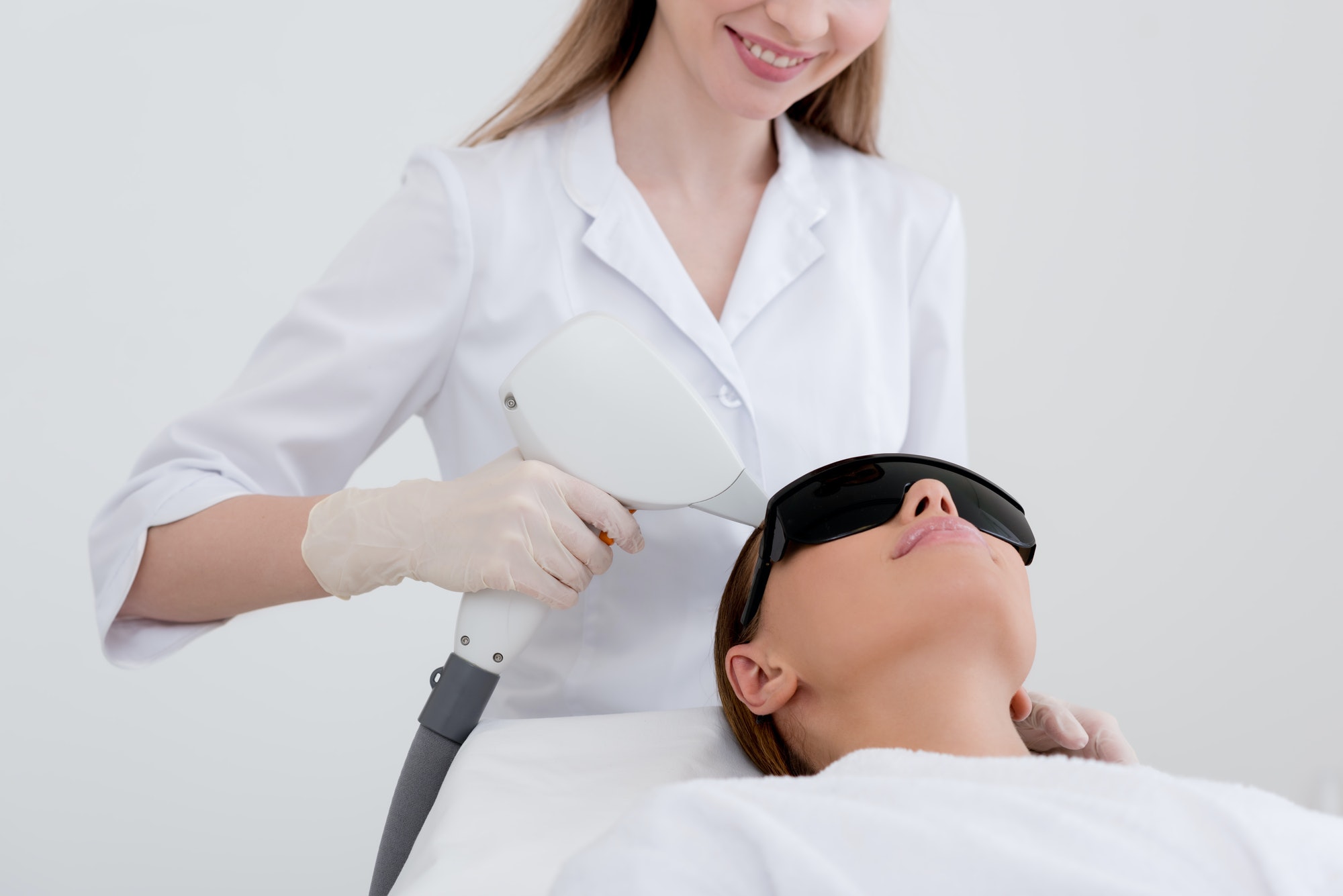 partial view of young woman receiving laser hair removal epilation on face in salon