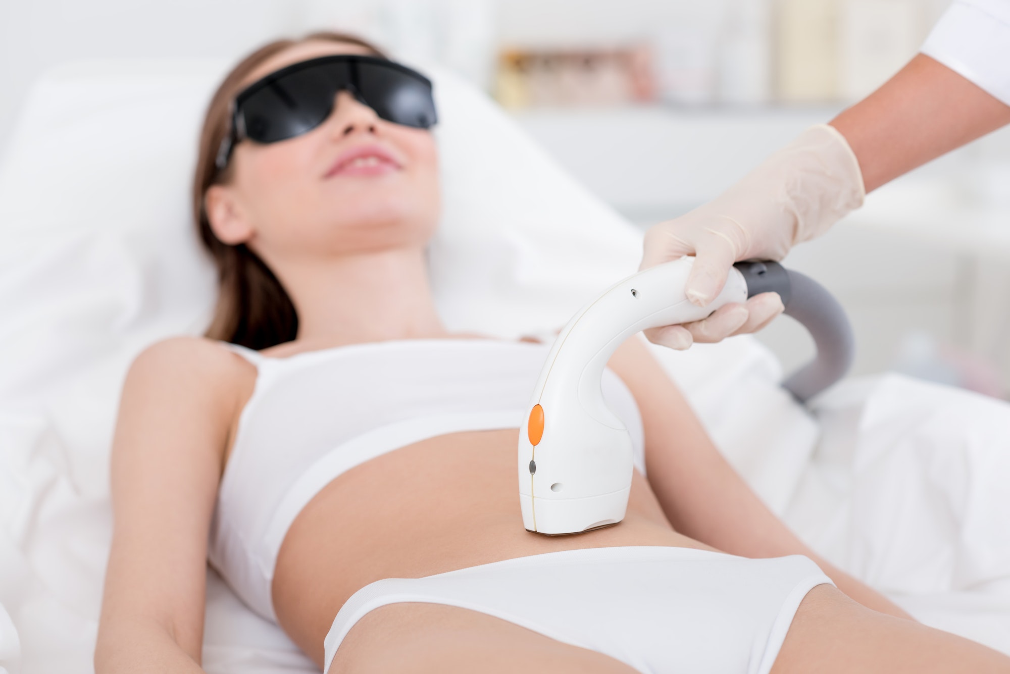 woman in underwear receiving laser hair removal procedure on stomach on salon